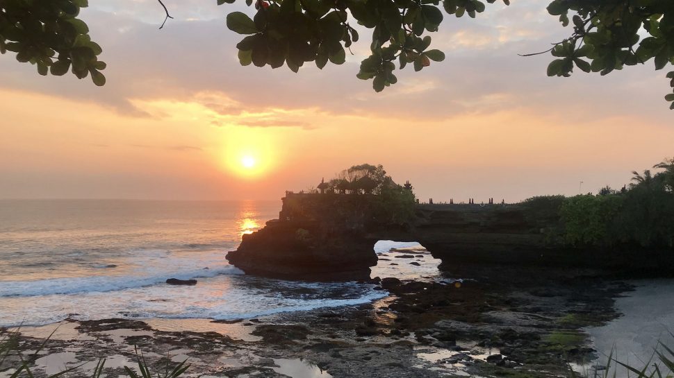 AA view of the sun setting over Tanah Lot, a sacred temple in Bali 